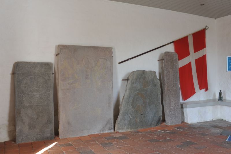 Runesten og gamle ligsten i kirkens våbenhus..